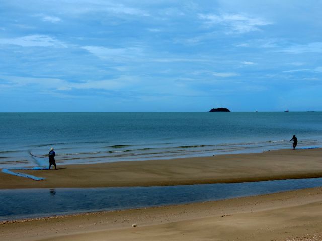 Die Fischer führen ihr Netz U-förmig am Strand entlang.